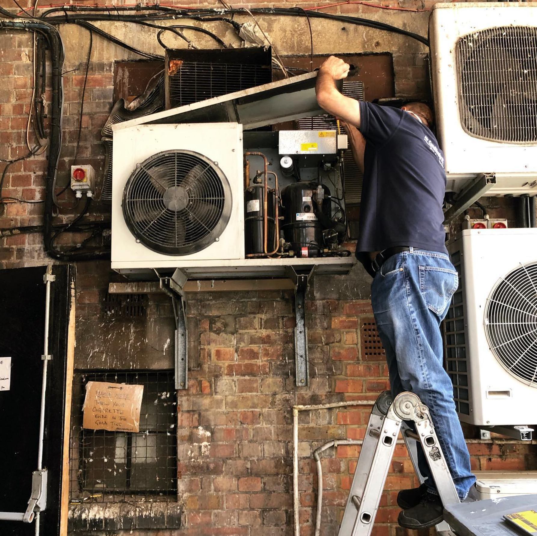 UK Refrigeration engineer maintaining outdoor air conditioning unit